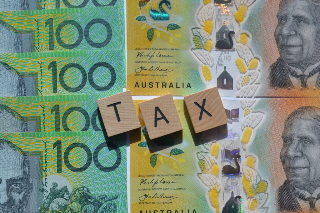 Tax, word in wood letters on top of Australian high denomination bank notes